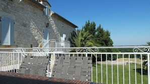 A stone building with a balcony and a view of the landscape.