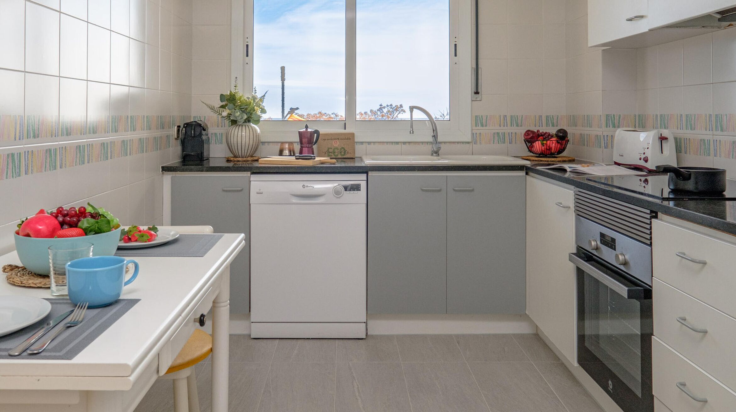 Una cocina moderna con lavavajillas, estufa y ventana con vistas a la ciudad.