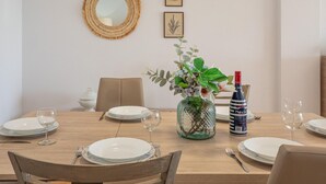 Een eettafel gedekt met borden, bestek en een fles Mare Solo wijn.