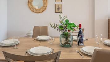 Una mesa de comedor preparada con platos, cubiertos y una botella de vino Mare Solo.