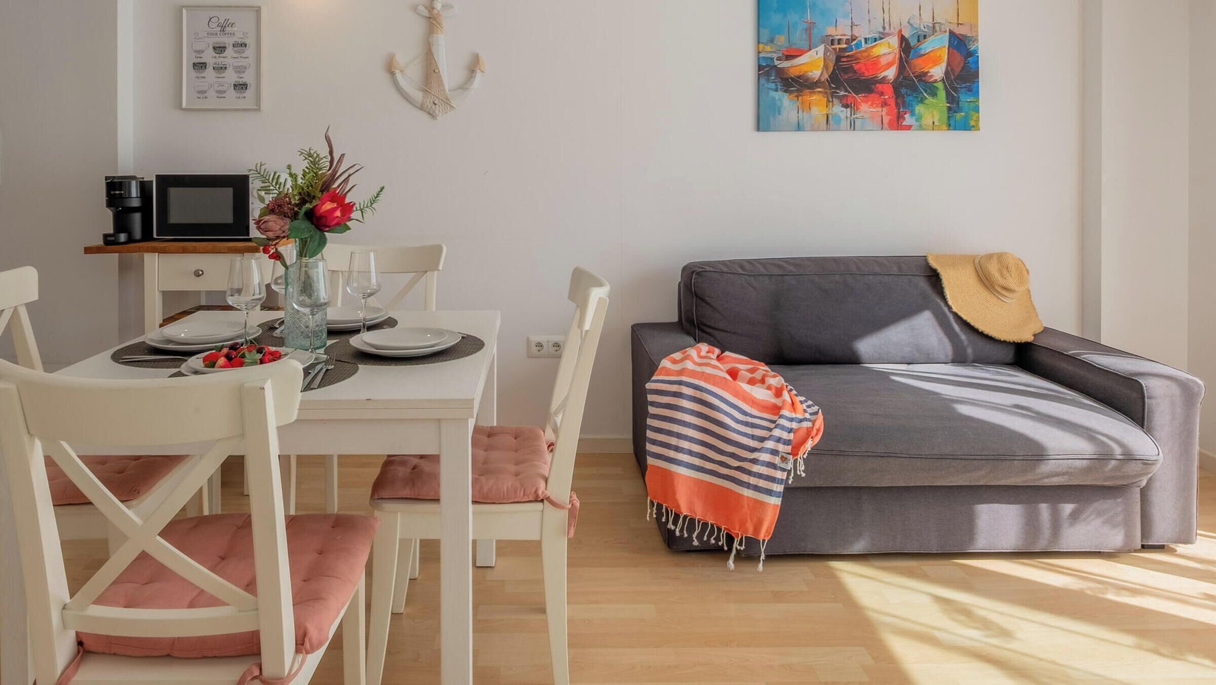 Un espace repas avec une table blanche, des chaises et une machine à café.
