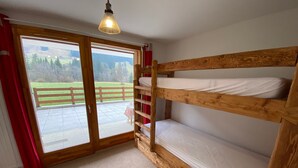 A room with a wooden bunk bed, a sliding glass door leading to an outdoor area, and a ceiling light fixture.