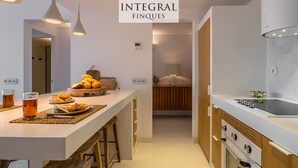 Une cuisine moderne dotée d’un îlot central, de tabourets en bois, d’un coin repas et offrant une vue sur le salon.