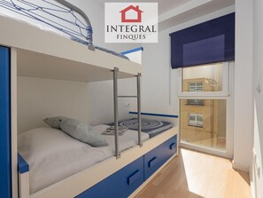 A bunk bed room with a window, a ladder, and a view of a building outside.
