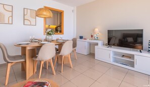 A modern living room with a dining area, a TV, and a white console.