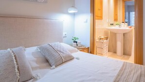 Ett hotellrum med en säng, ett nattduksbord, en lampa och utsikt över badrummet.