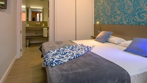 Een hotelkamer met een bed, nachtkastjes, een spiegel, een badkamer met een wastafel en spiegel, en een behangen muur.