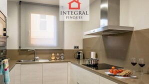 Een moderne keuken met een roestvrijstalen afzuigkap, een ingebouwde oven en een raam boven de spoelbak.