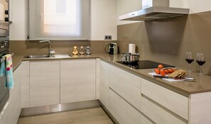 A modern kitchen with a stainless steel range hood, a built-in oven, and a window above the sink.