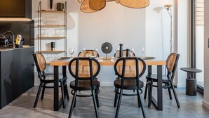 A modern dining area with a wooden table, black chairs with woven seats, and a central decorative item. - Modern Penthouse with Terrace & AC - Palamós (Palamós)