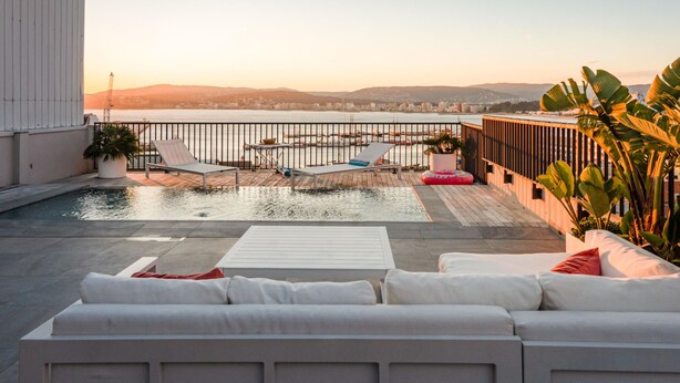 A rooftop terrace with a pool, lounge chairs, and a view of the cityscape at sunset. - Modern Penthouse with Terrace & AC - Palamós (Palamós)