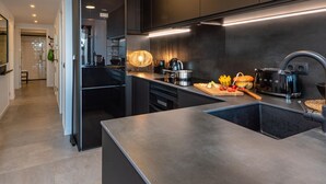 A modern kitchen with a central island, dark cabinetry, and stainless steel appliances. - Modern Penthouse with Terrace & AC - Palamós (Palamós)