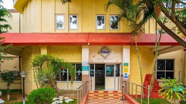 Un edificio con toldo rojo, un letrero y un camino a cuadros que lleva a la entrada.