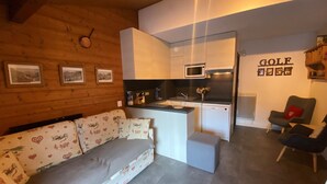 Un salón acogedor con sofá, una pequeña cocina y una mesa de comedor.