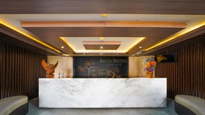 A reception desk at the Brit's Hotel with a modern design, including a marble counter and a TV screen above it. - Brits Hotel Legian (Kuta)