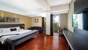 A modern hotel room with a large bed, a desk, and a balcony with a view. - Brits Hotel Legian (Kuta)