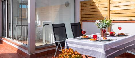 A dining area with a table set for two, a wooden fence, and a sign reading "INTEGRAL FINQUES".