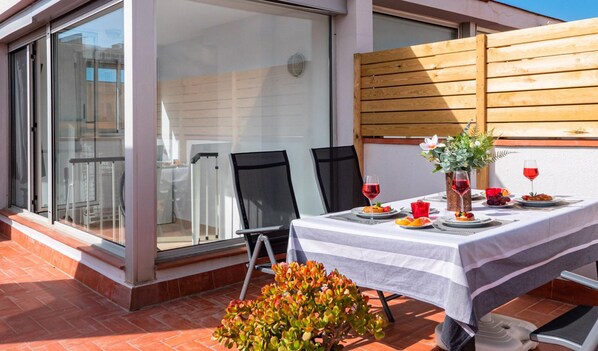 A dining area with a table set for two, a wooden fence, and a sign reading "INTEGRAL FINQUES".