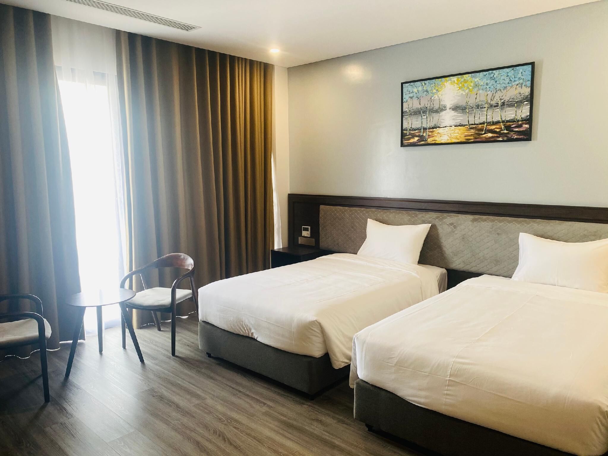 Una habitación de hotel con dos camas, un escritorio, una silla y un cuadro en la pared.