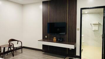 A modern bathroom with a shower, a vanity with a mirror, and a television mounted on the wall.