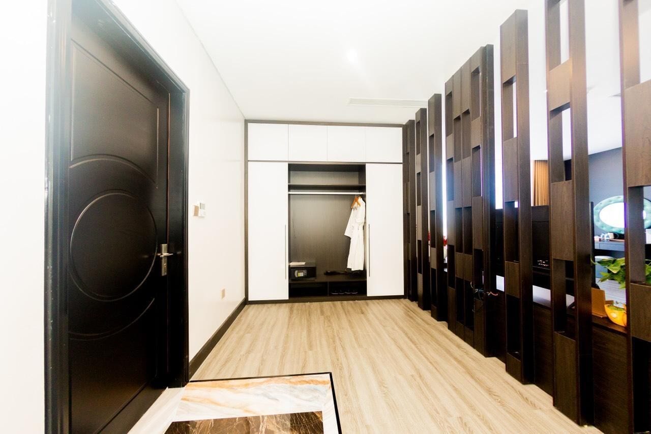 A hallway with a black door, a white closet with a hanging robe, and a wooden partition with shelves.