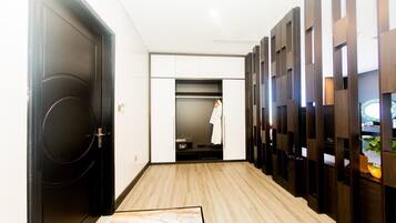 A hallway with a black door, a white closet with a hanging robe, and a wooden partition with shelves.