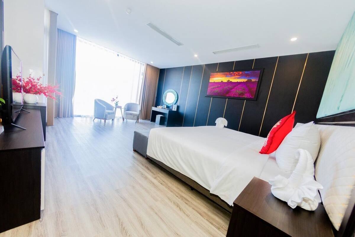 Habitación de hotel moderna con una cama grande, un escritorio, una silla, un televisor y vistas al exterior.