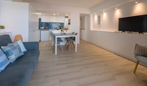 A modern apartment with a dining area, kitchen, and living room.