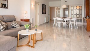 A modern living room with a sofa, coffee table, and dining area with chairs.