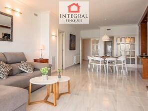 A modern living room with a sofa, coffee table, and dining area with chairs.