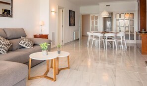 Un salon moderne avec un canapé, une table basse et un coin repas avec des chaises.