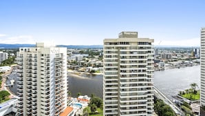 Un hôtel de grande hauteur doté de nombreux balcons, offrant une vue sur le front de mer et donnant sur une marina en arrière-plan.