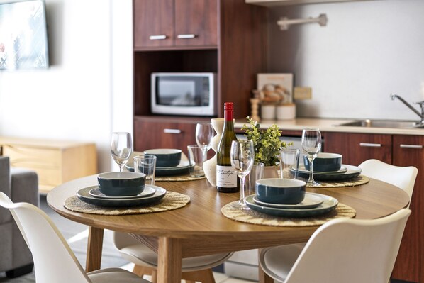 A dining table set with blue plates, wine glasses, and a bottle of wine, surrounded by white chairs.