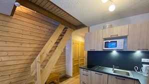 A kitchen with wooden cabinets, a microwave, and a sink. - Bright apartment near Linga with WiFi and parking, South/East balcony (Châtel)