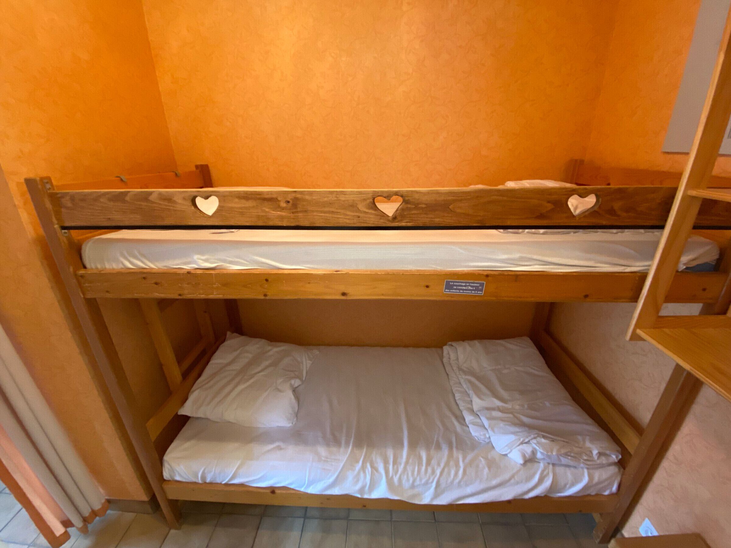 A bunk bed with two levels, each with a mattress and pillows.