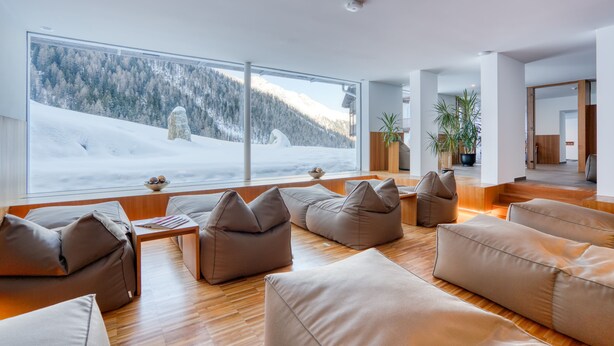 A modern living room with a large window overlooking a snowy mountain landscape.