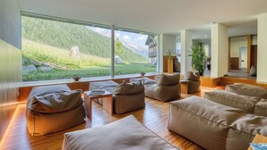 A modern living room with large windows, wooden flooring, and beige sofas.
