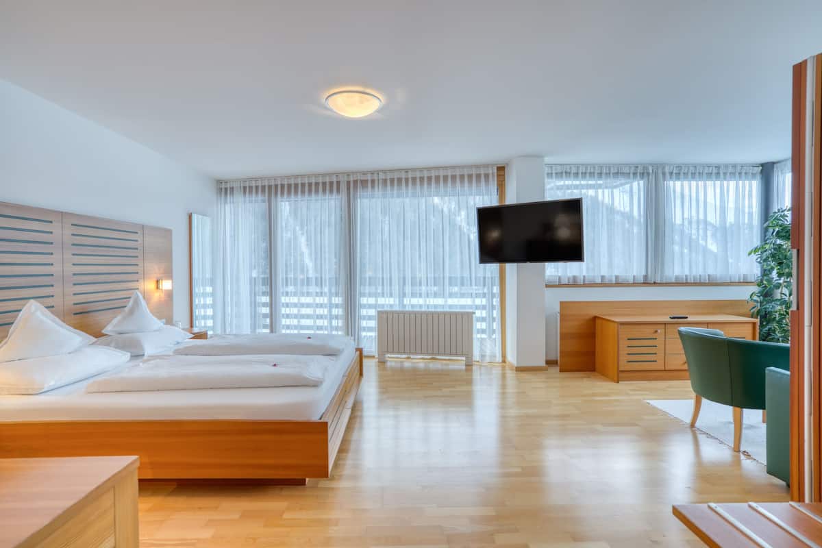 Una habitación de hotel moderna con una cama grande, un televisor, un escritorio y una silla.