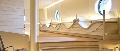 Un spa moderno con un diseño arquitectónico singular, que presenta una escalera central y varias zonas de estar.