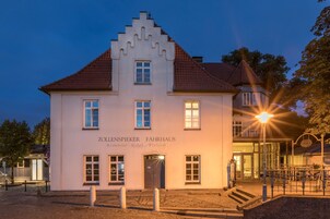 Un edificio blanco con tejado de tejas rojas, con la leyenda 'Zollenspieker Fahrhaus Restaurant Hotel Festsaal'.