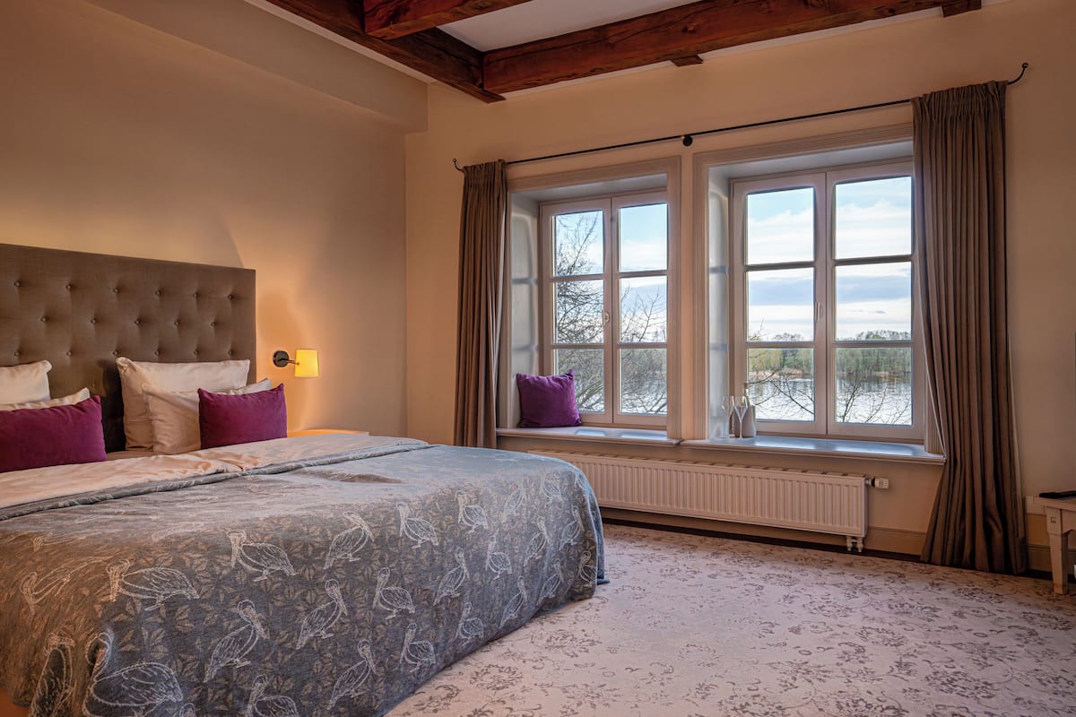Une chambre avec un grand lit, une fenêtre avec des rideaux et une vue sur l’extérieur.