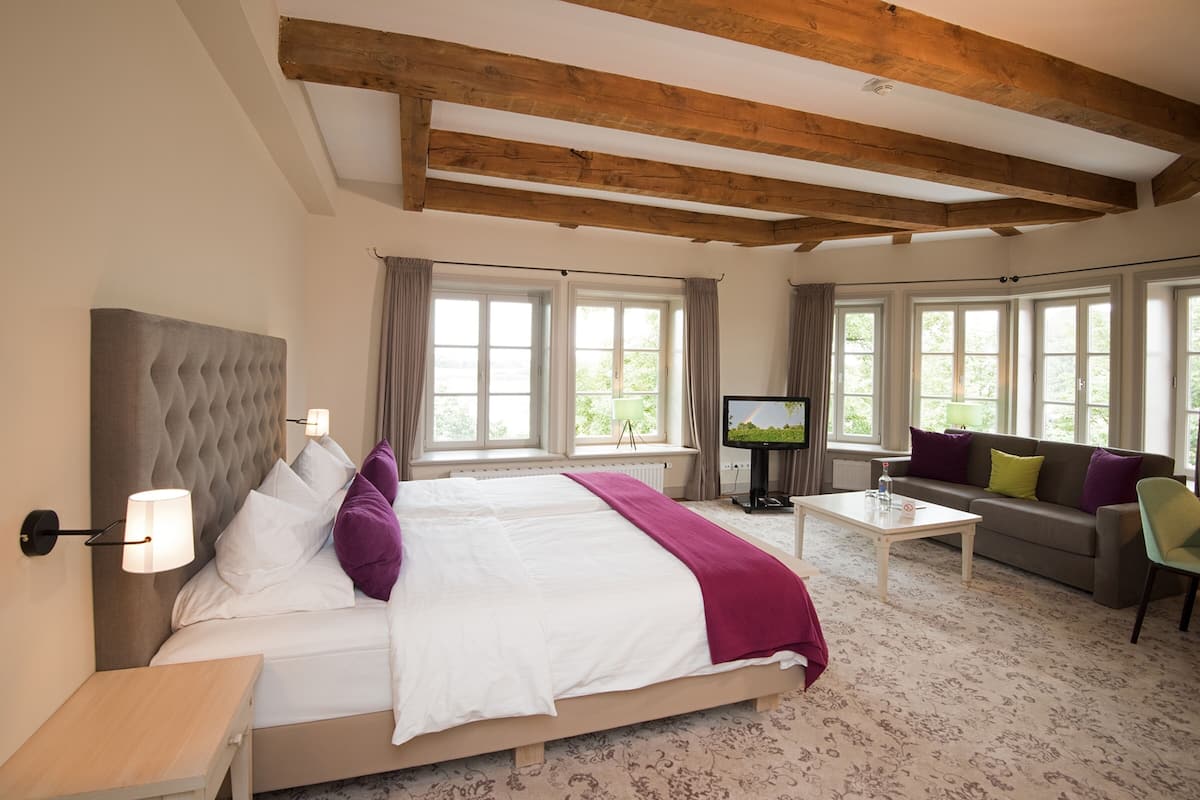 Une chambre d’hôtel avec un grand lit, une télévision, un canapé et une table basse.