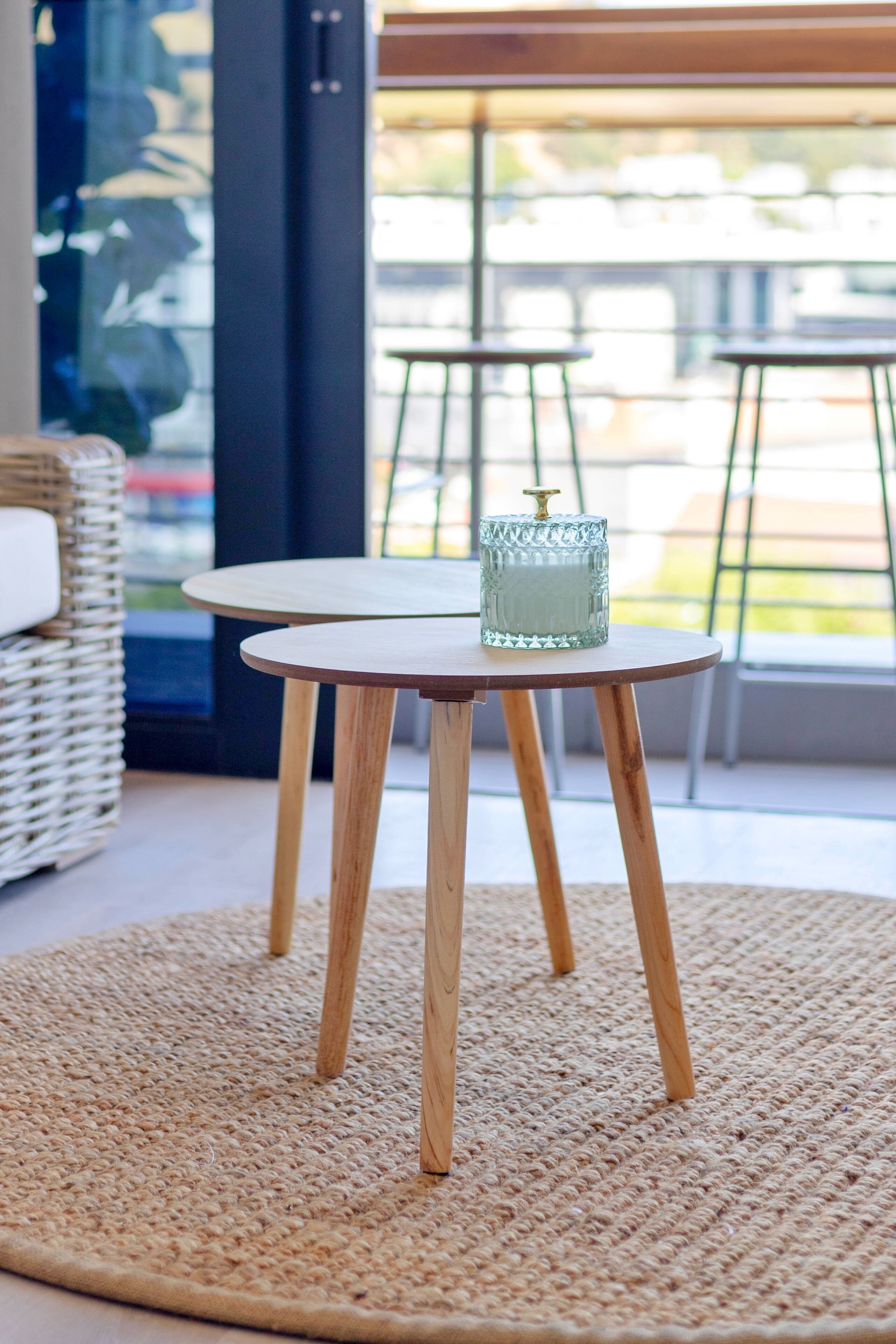 Une table ronde en bois sur laquelle repose un chandelier en verre, le tout posé sur un tapis tissé.