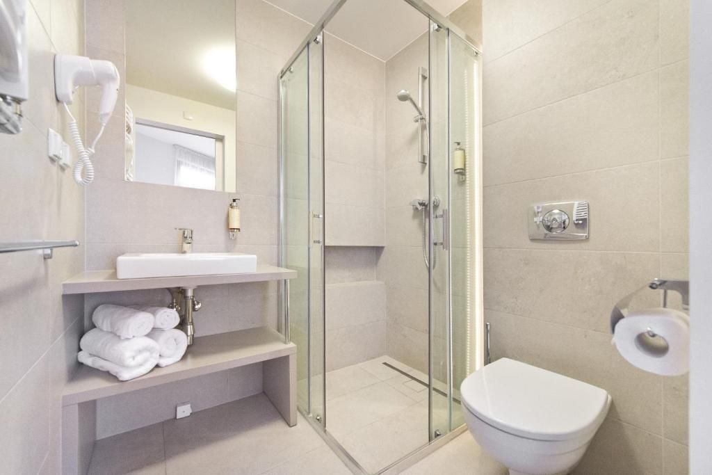 Ein modernes Badezimmer mit einer gläsernen Dusche, einem weißen Waschbecken und einer Toilette.