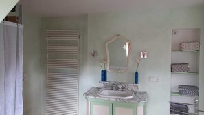 Une salle de bain avec un lavabo en marbre, un miroir et une étagère contenant des articles de toilette.