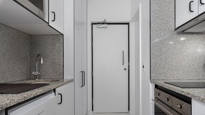 A modern kitchen with white cabinetry, granite countertops, a stainless steel sink, and a built-in oven. - The Flamingo 708 (Cape Town)