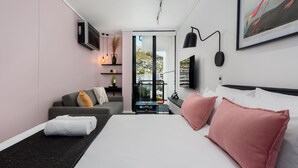 A modern hotel room with a large bed, a sofa, a desk, and a view of the city. - The Flamingo 708 (Cape Town)