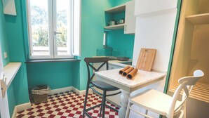 Une cuisine aux murs de couleur turquoise, avec un sol à carreaux et une fenêtre donnant sur des arbres.