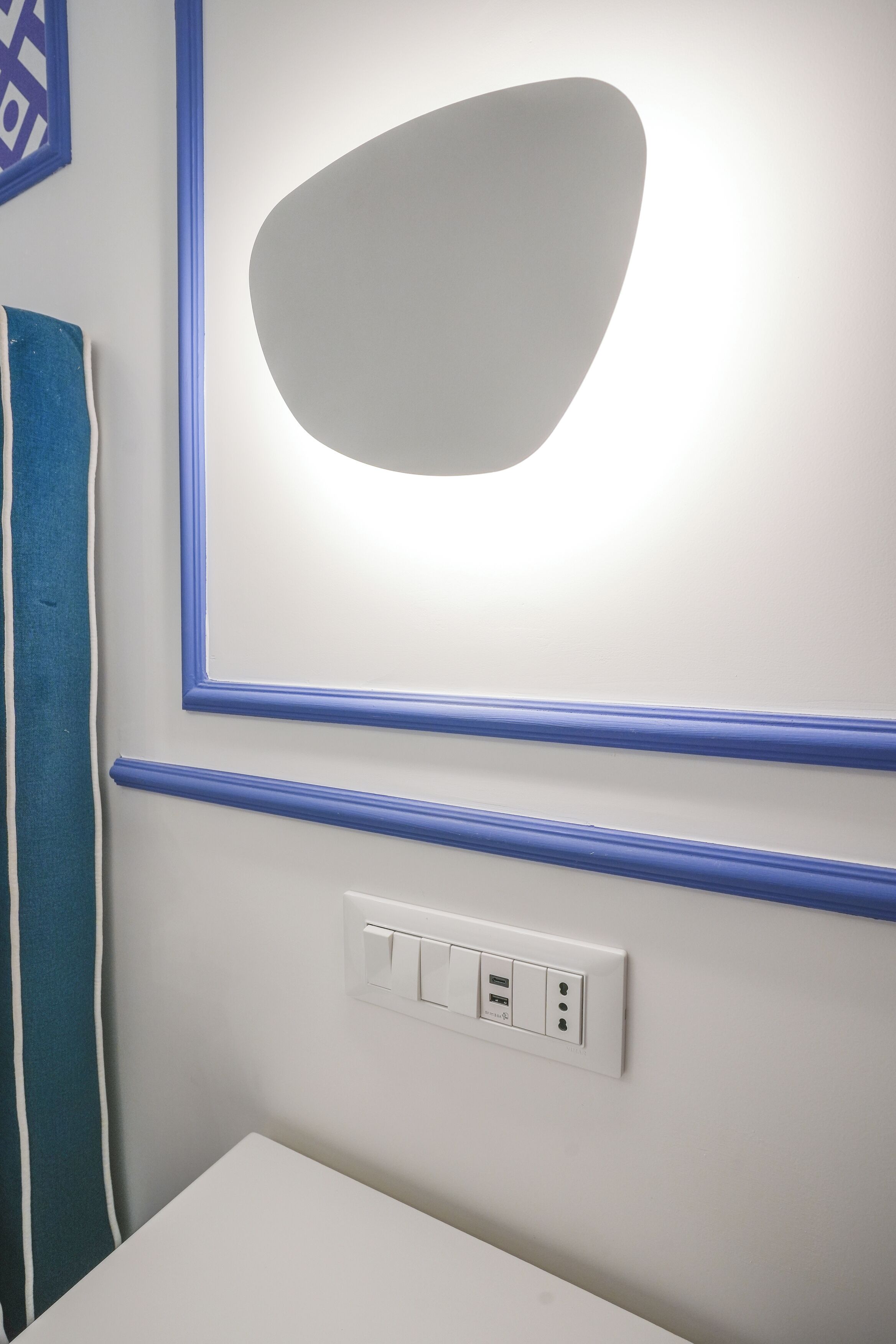 A bathroom with a white sink, a mirror with a blue frame, and a towel rack with a blue towel.