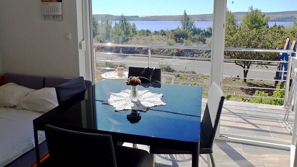 A room with a balcony, a table with a vase, and a bed.